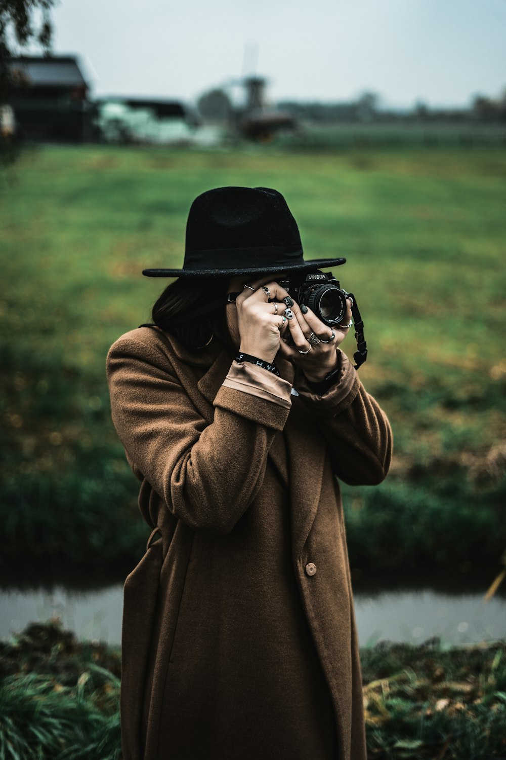 man in brown coat holding black camera