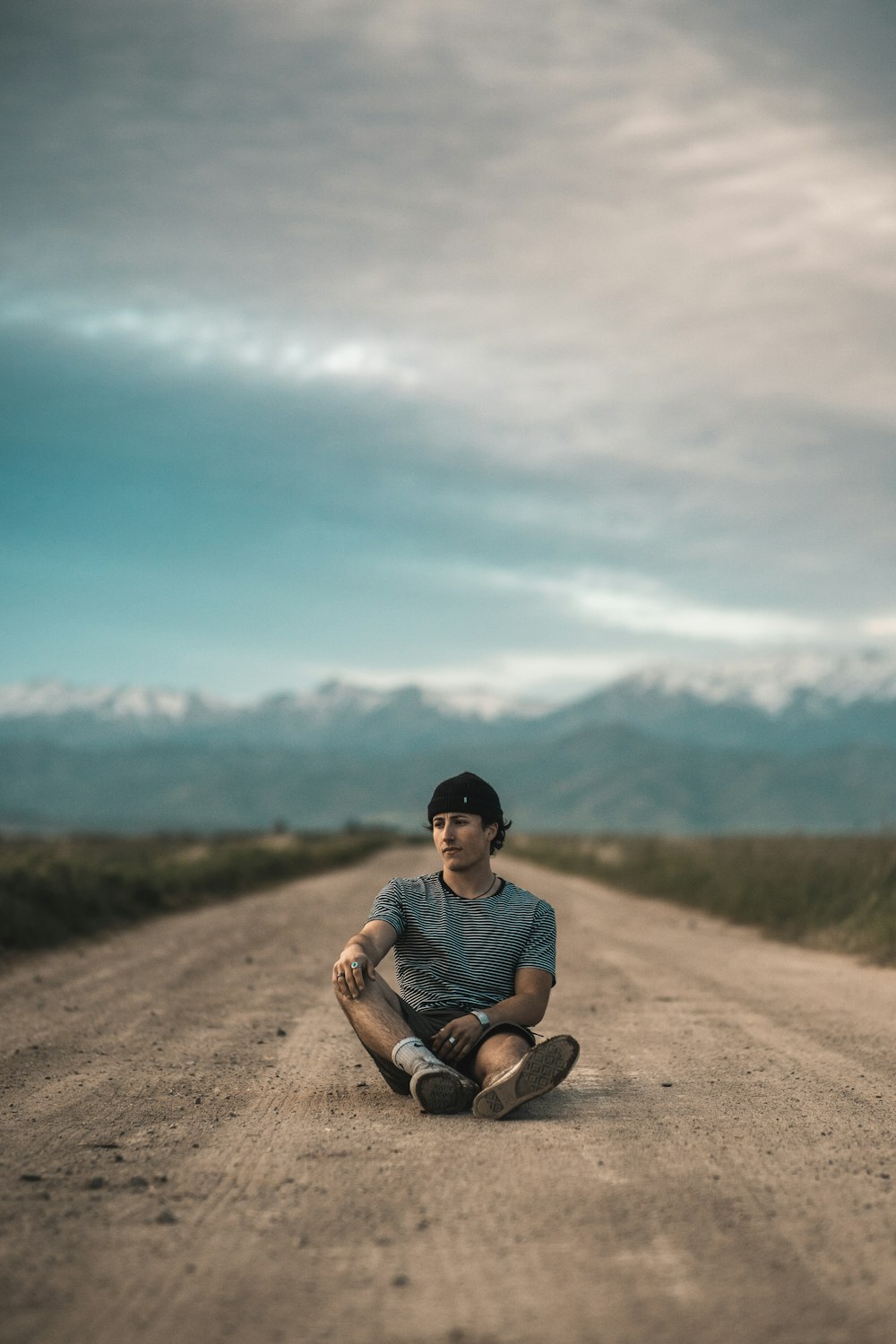 man in blue crew neck t-shirt sitting on brown dirt road during daytime