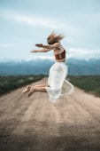woman in white dress running on brown dirt road during daytime