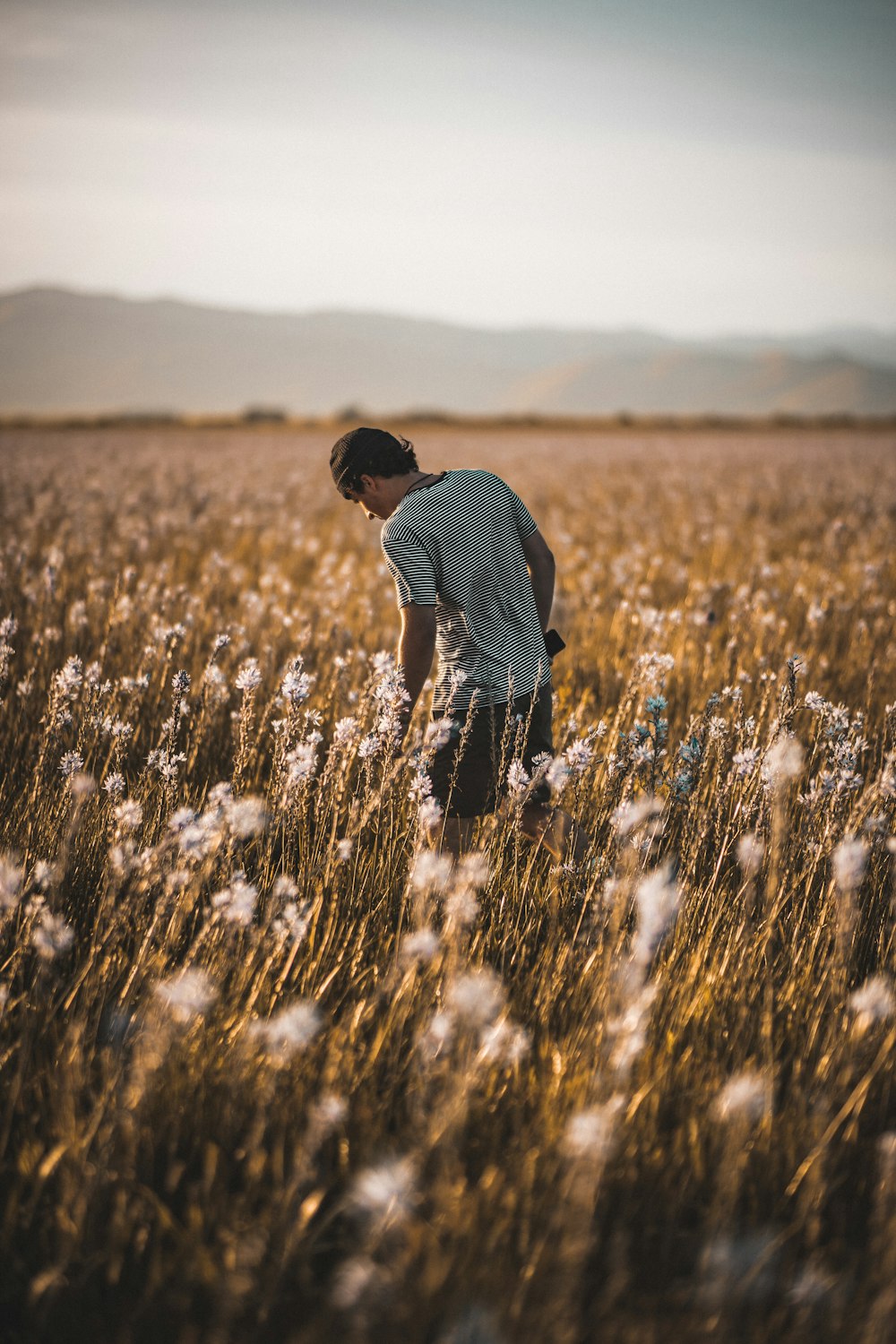 man in blue and white plaid shirt walking on brown grass field during daytime