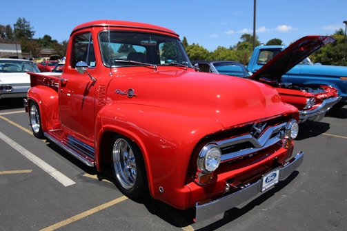 A gleaming vintage truck with a fresh custom paint job parked under string lights at sunset.