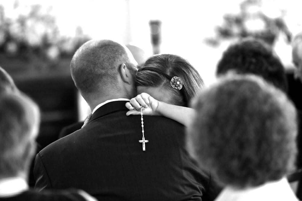 man in black suit kissing woman in black and white photo