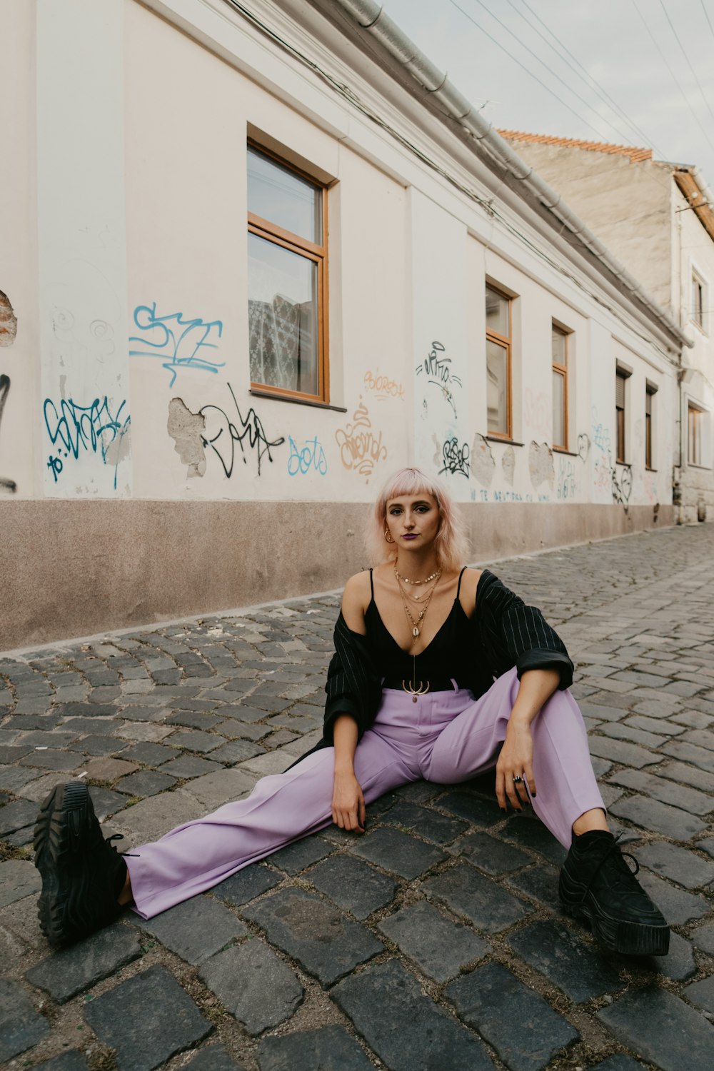 woman in black tank top and purple pants sitting on gray concrete floor