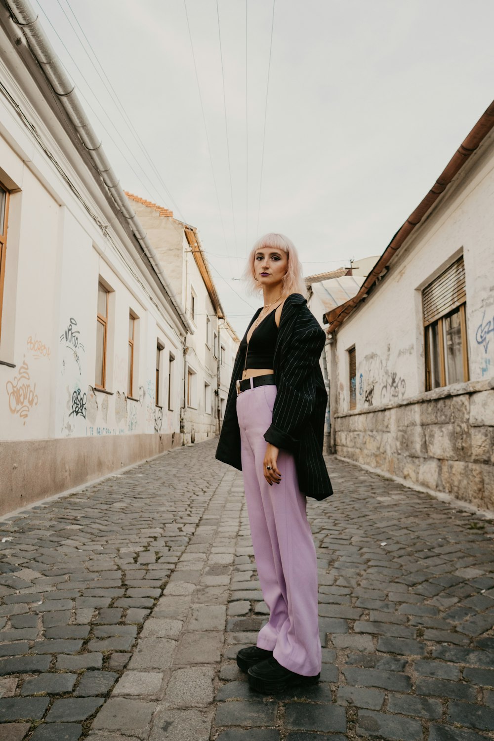 woman in black and pink long sleeve dress standing on gray brick floor during daytime