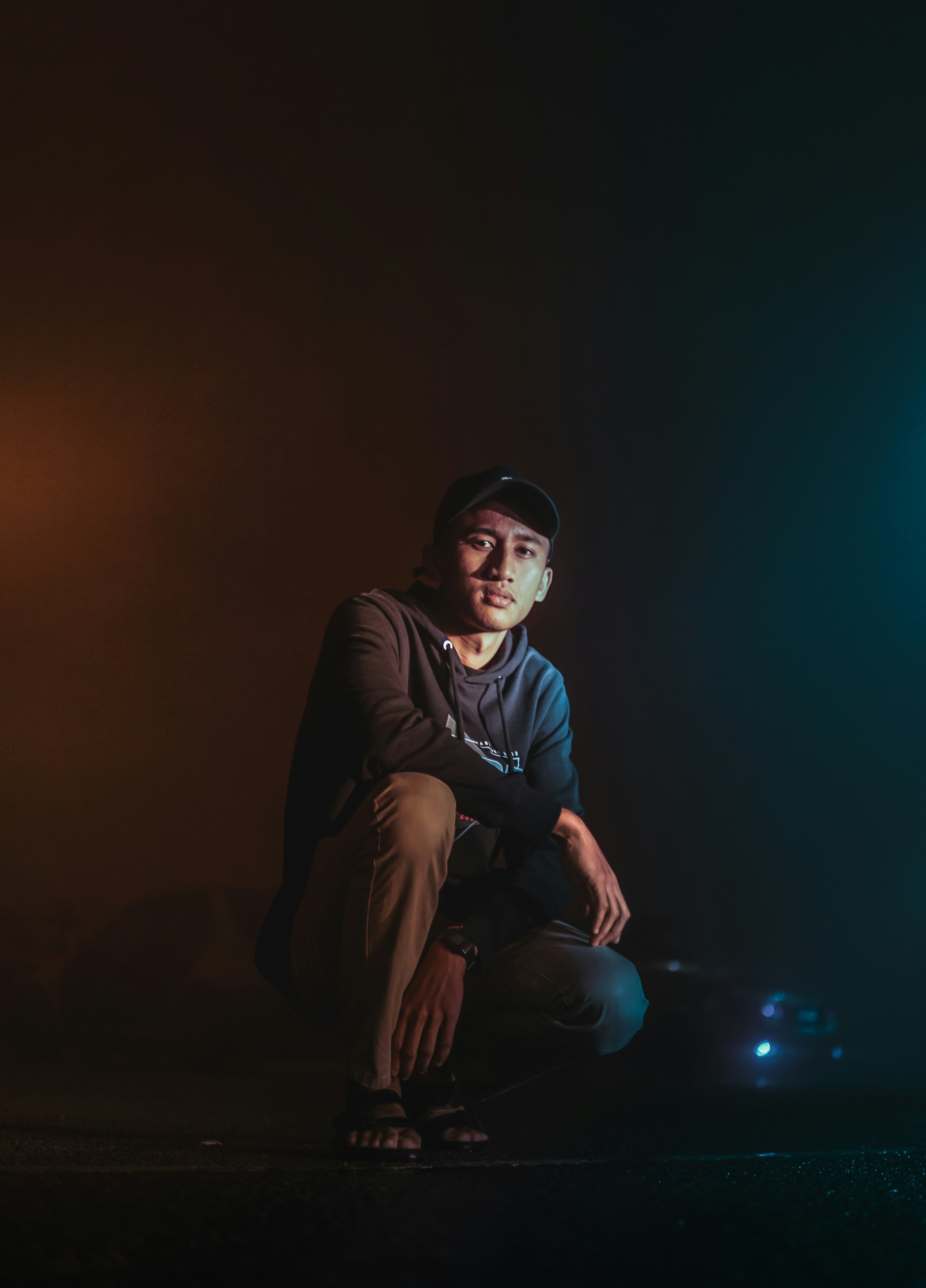 hombre con chaqueta negra y pantalón negro sentado en el suelo