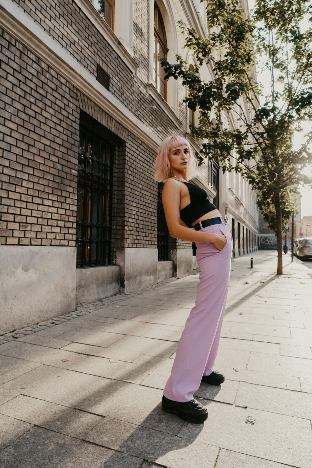 woman in black tank top and pink pants standing on sidewalk during daytime