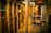A dimly lit server room with multiple racks of computer servers surrounded by cables and various technical equipment. The space has an industrial feel with visible pipes and ductwork, and a sign on one rack stating 'Do not use'.