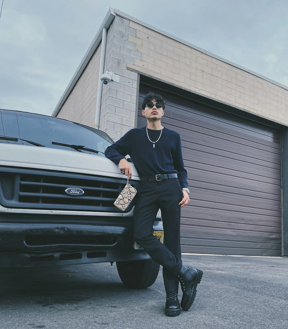 man in black jacket and black pants standing beside black car