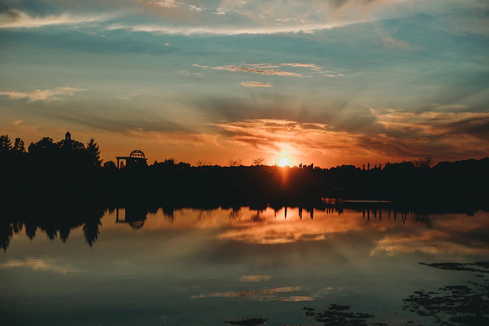 Serene sunset over lake with calm water reflecting vibrant colors behind the horizon