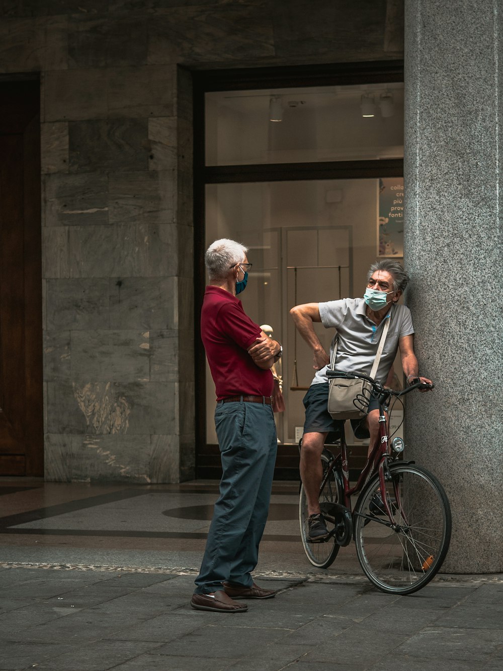 Homme en t-shirt rouge et jean en jean bleu debout à côté d’une femme en t-shirt gris