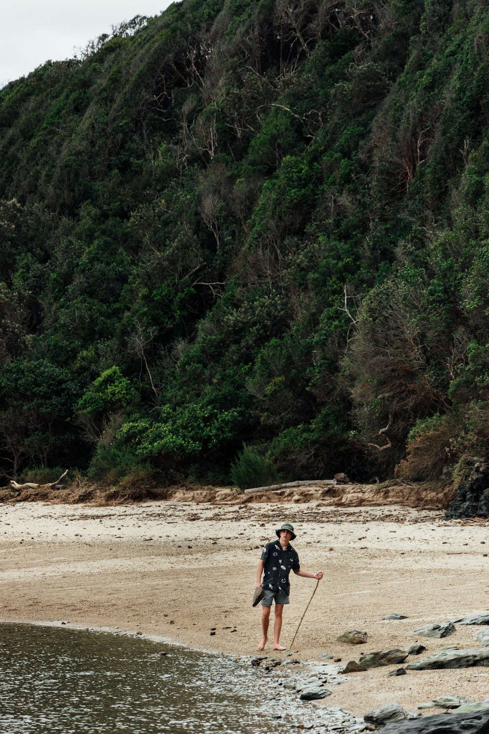 man in black shirt and blue denim jeans walking on brown sand during daytime