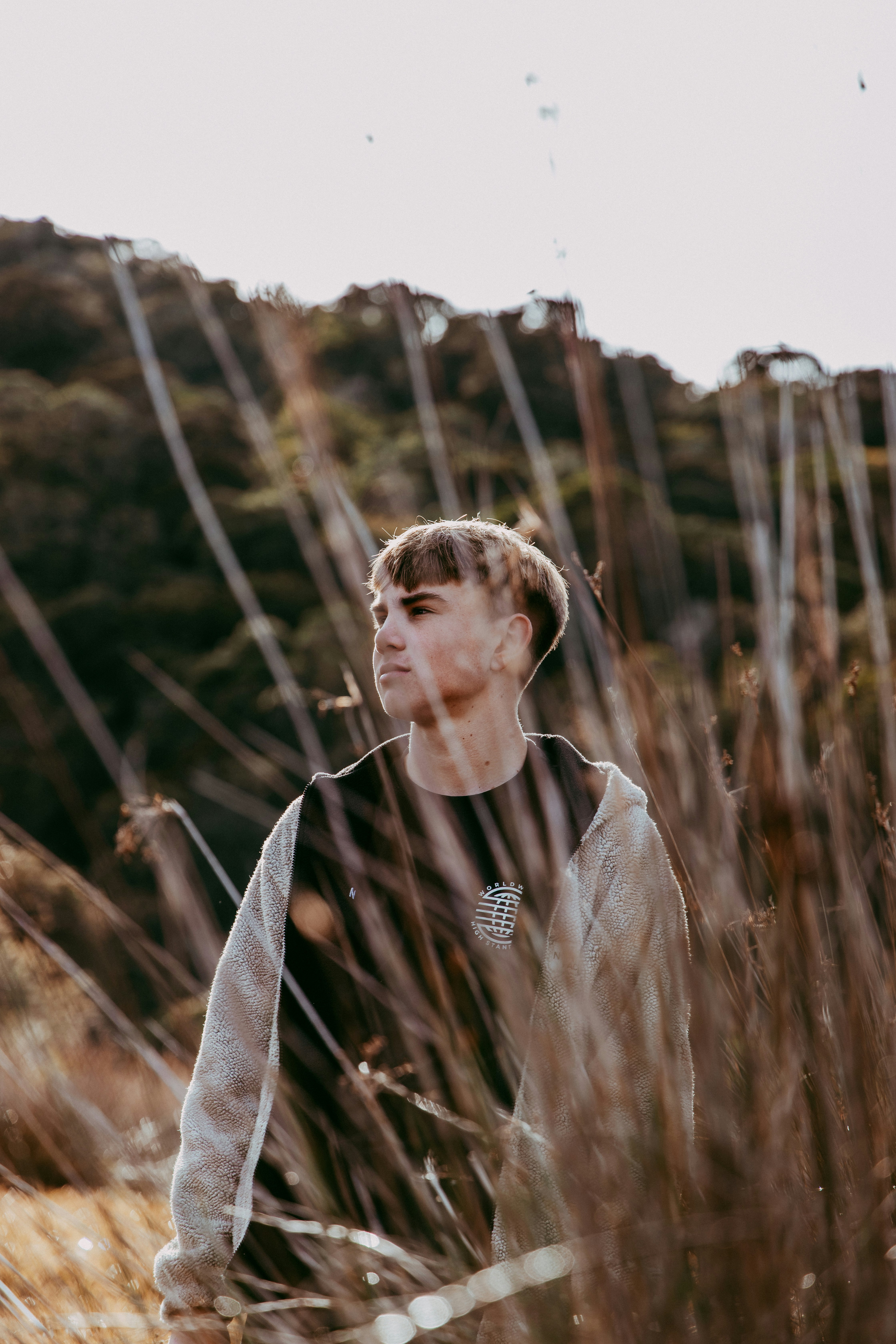 woman in white and black stripe shirt standing on brown grass field during daytime