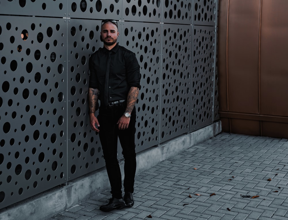 man in black jacket standing beside brown wooden door