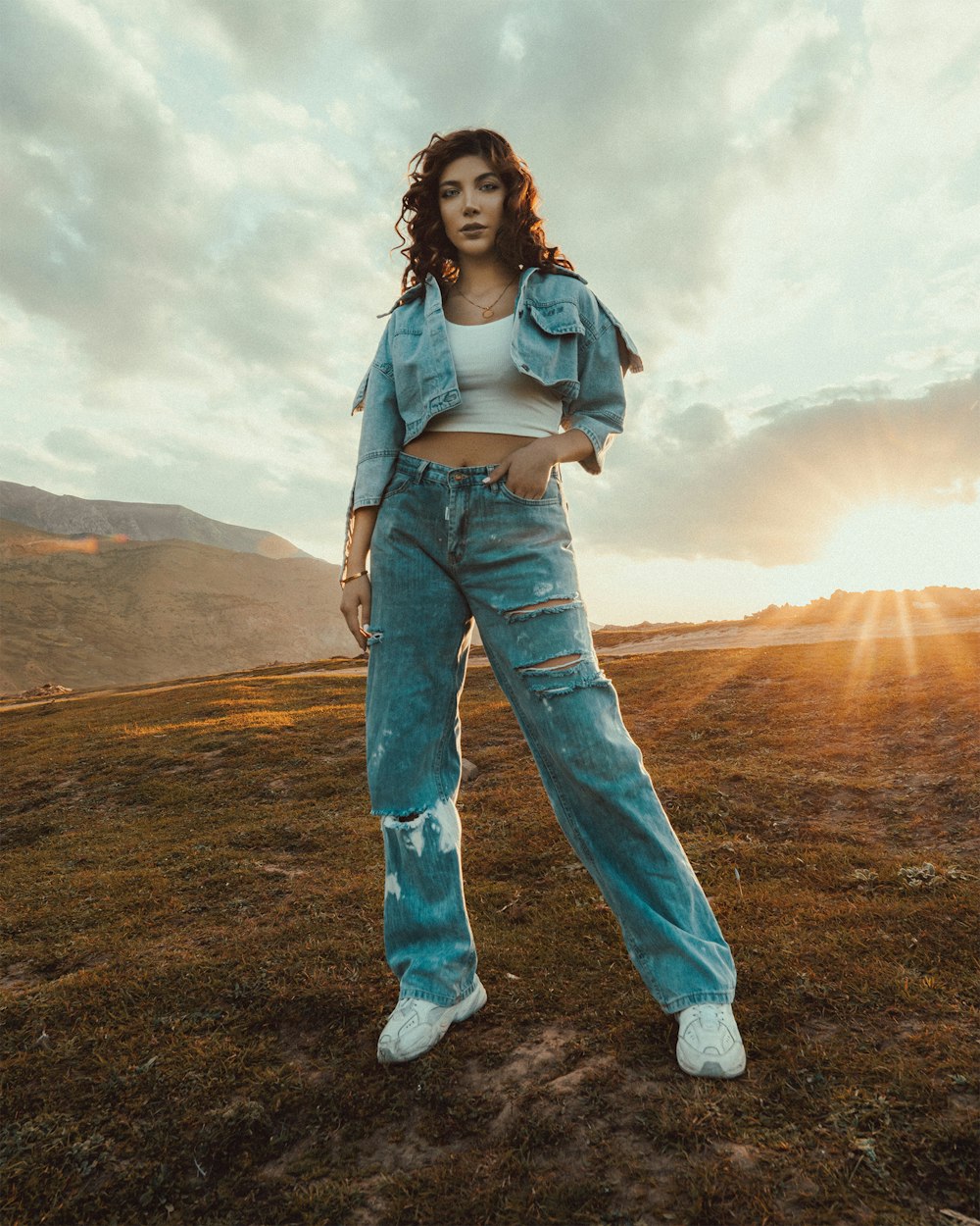 woman in blue denim jeans standing on green grass field during daytime