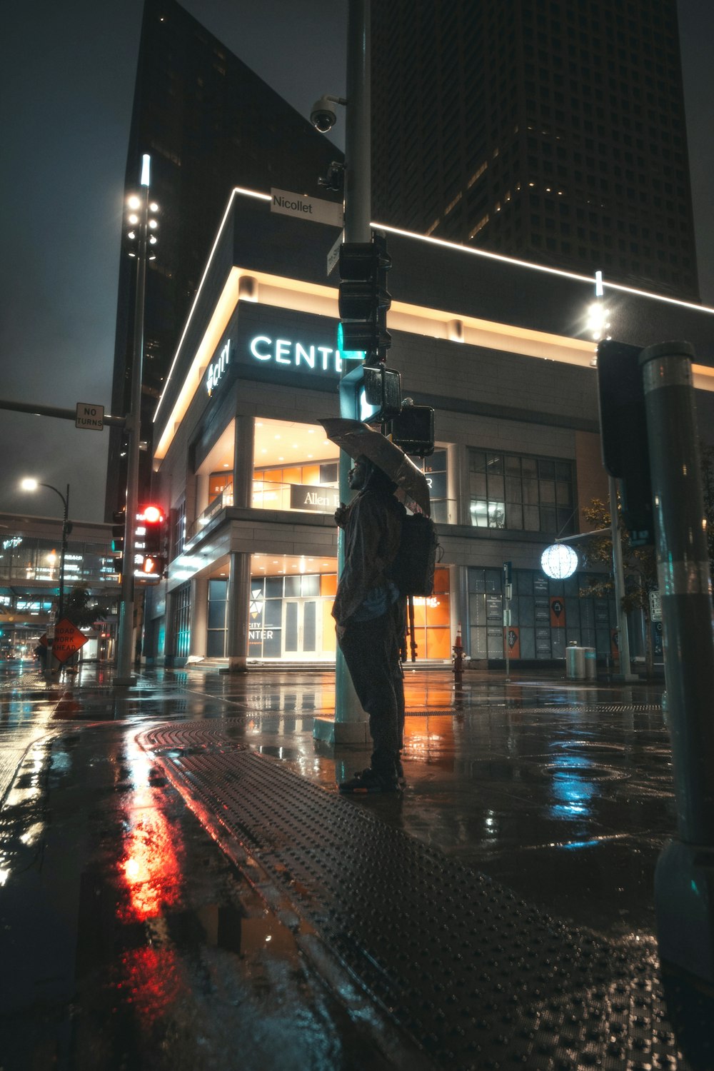 man in black jacket and black pants standing on street during night time