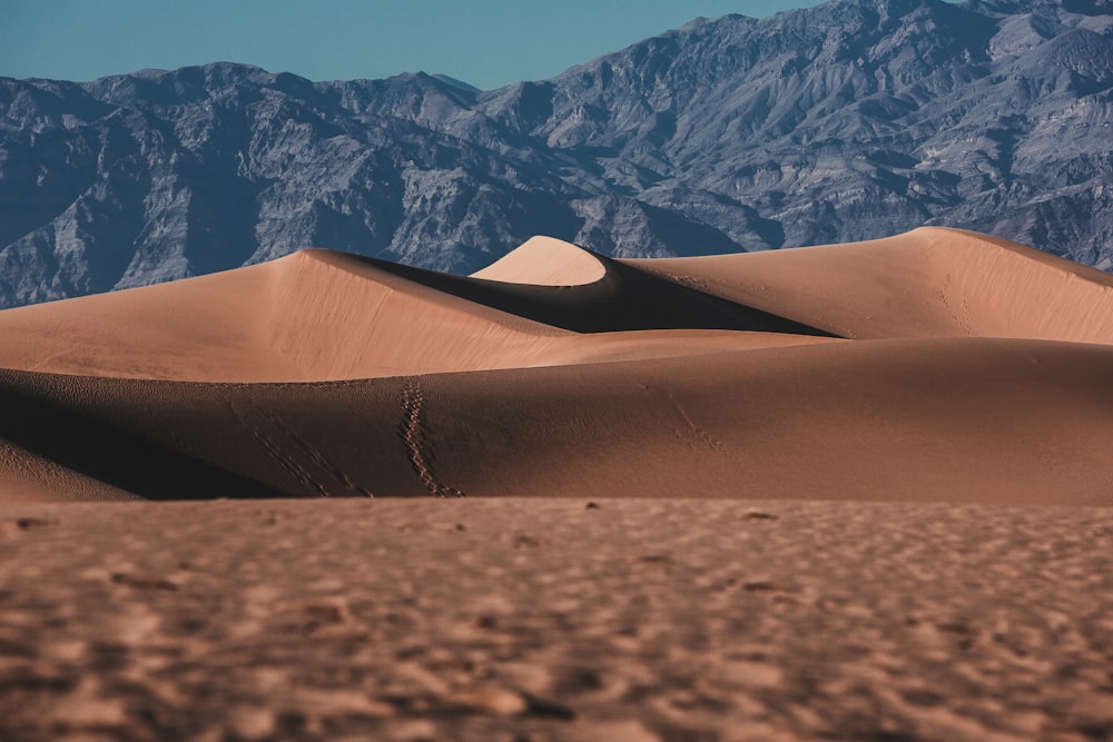 brown sand near snow covered mountain during daytime