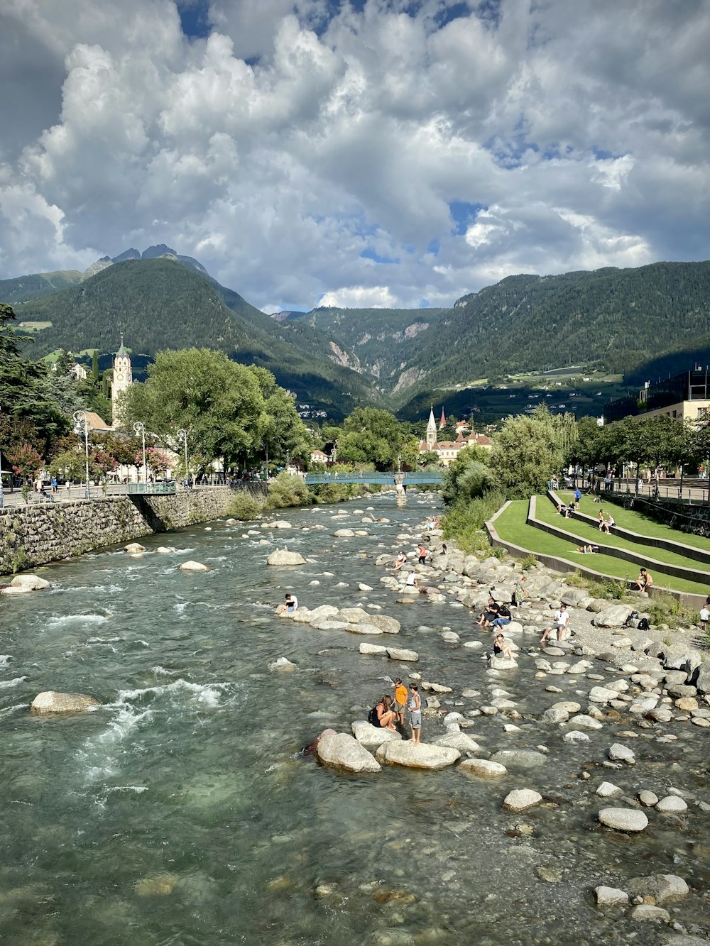 Persone in acqua vicino al campo verde dell'erba e alla montagna verde durante il giorno