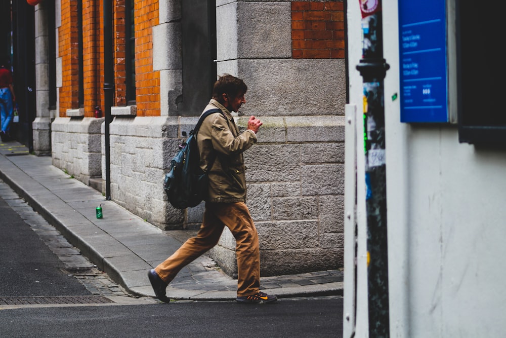 man in brown jacket and brown pants walking on sidewalk during daytime