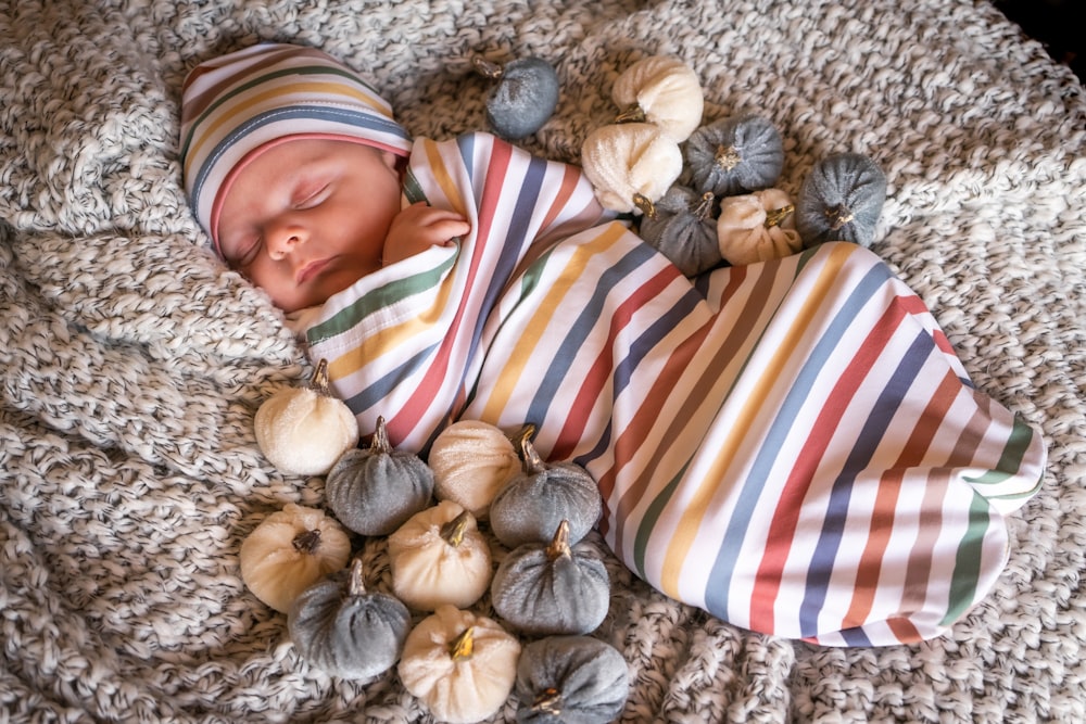 주황색 흰색과 파란색 줄무늬의 아기는 갈색과 흰색 직물에 누워 있습니다.