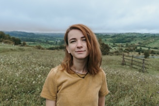 woman in yellow crew neck t-shirt standing on green grass field during daytime