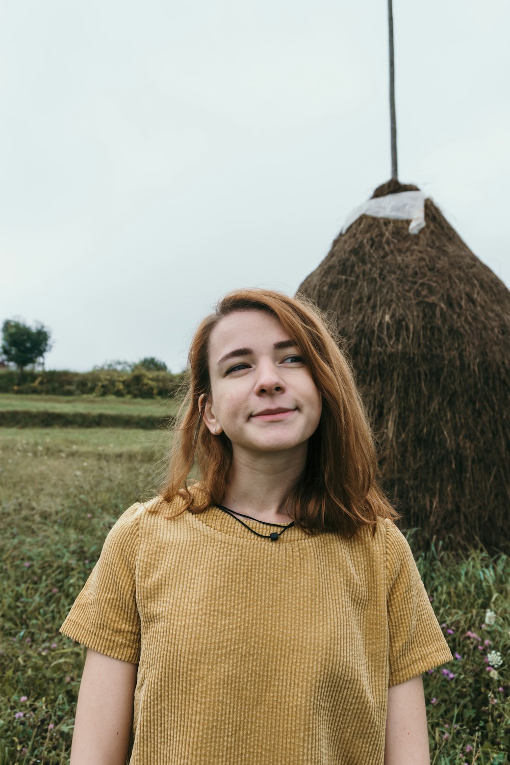 woman in yellow sweater standing on green grass field during daytime