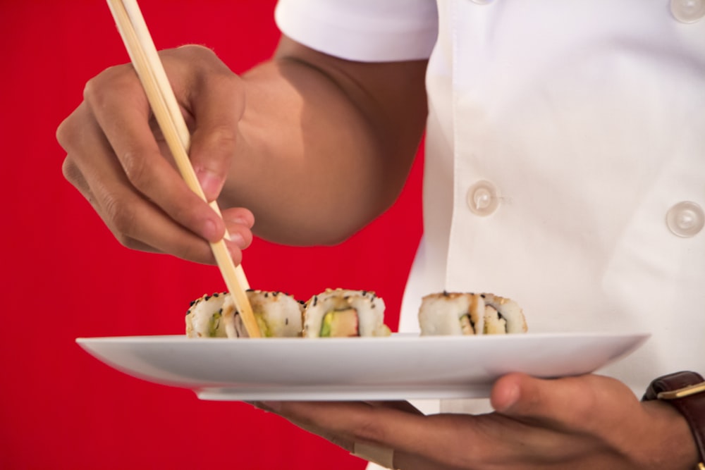 person holding chopsticks with food on plate