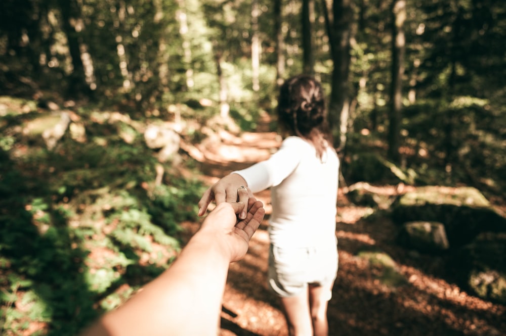 woman in white long sleeve shirt and white shorts standing in forest during daytime