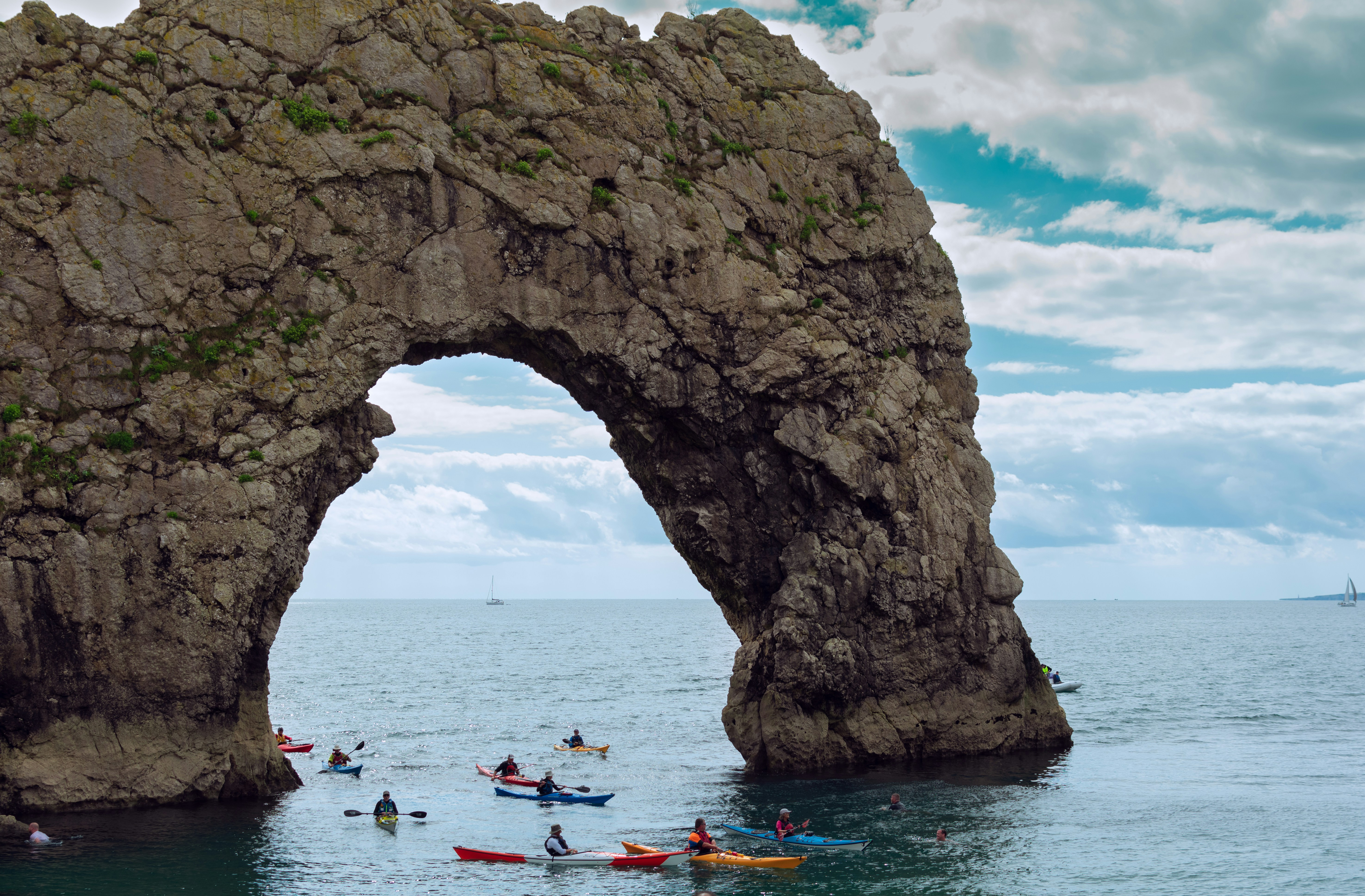 personnes se déplaçant sur un bateau sur la mer près d’une formation rocheuse pendant la journée