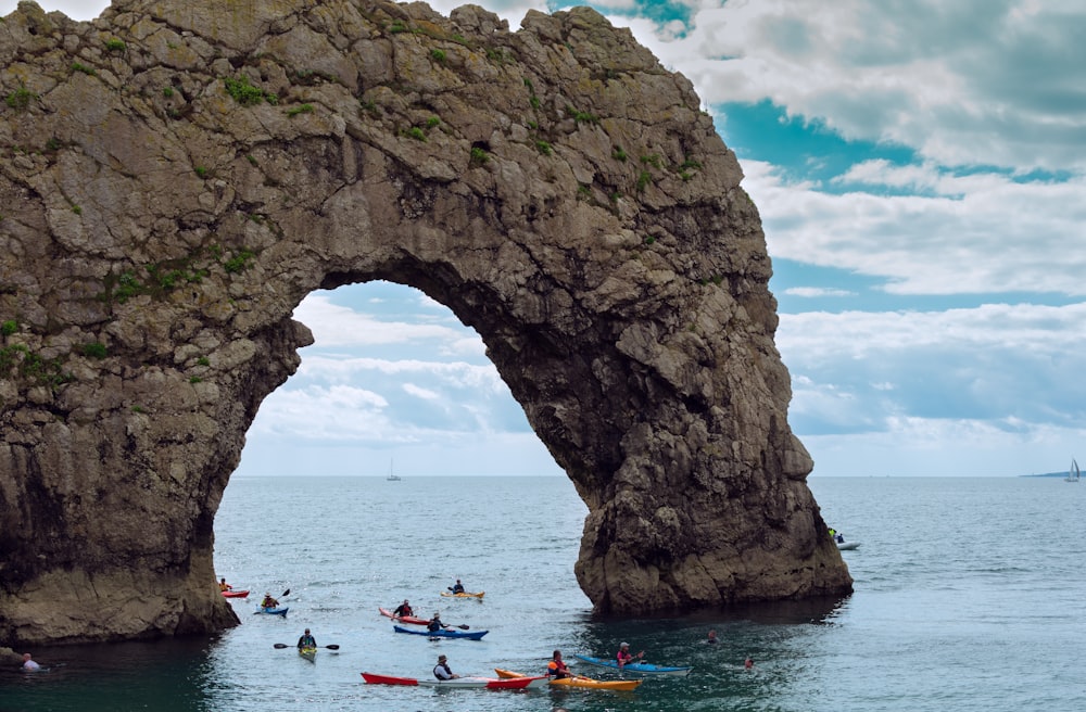 people riding on boat on sea near rock formation during daytime