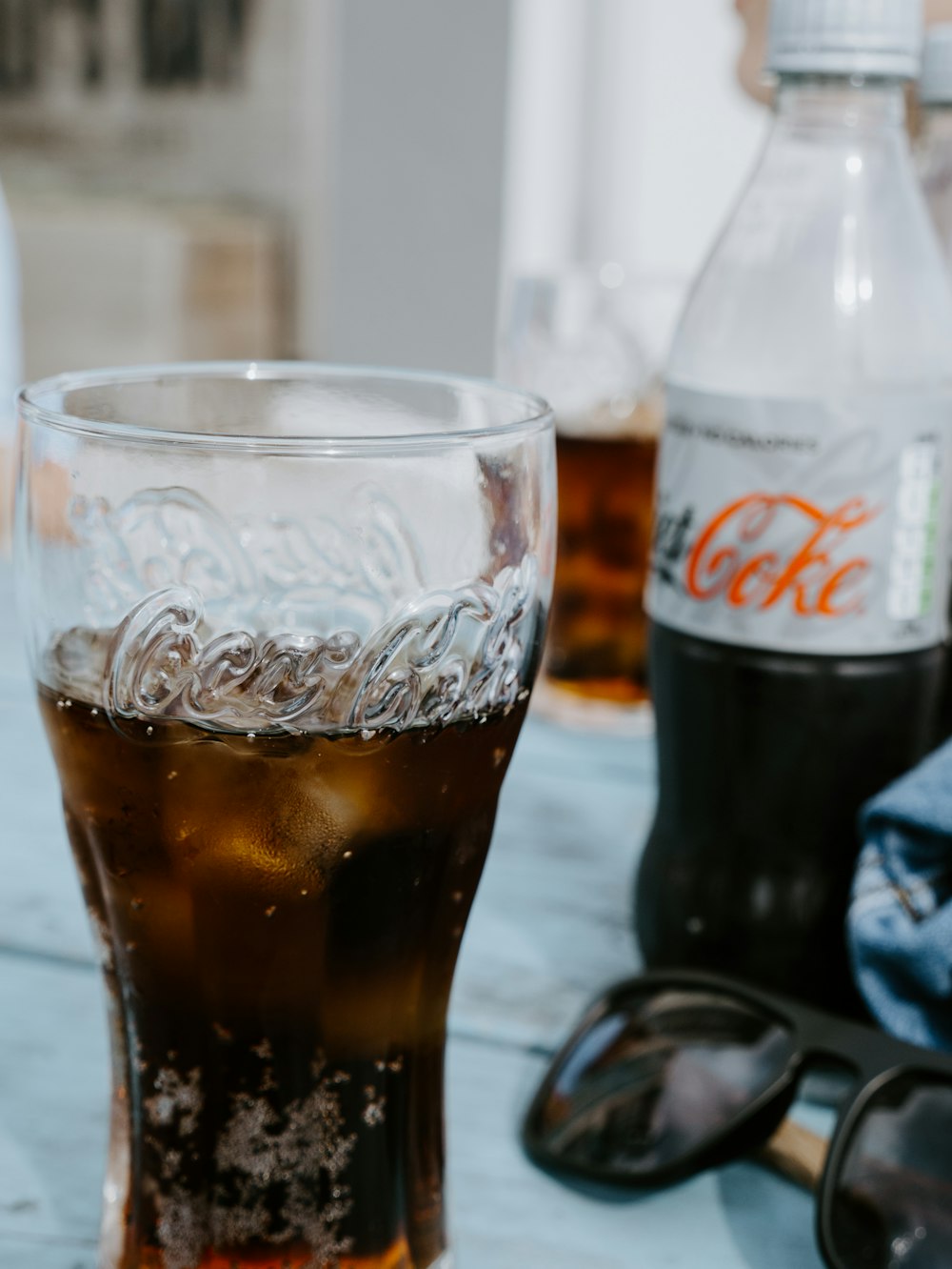 coca cola light bottle beside clear drinking glass