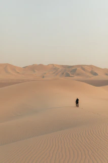 A cinematic shot of Monika walking thoughtfully near Angkor Wat, soft sand hues blending with the ancient stone.