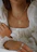 Close-up of a woman wearing delicate gold jewelry from aurelia noir, her hand gently touching a black velvet pouch.