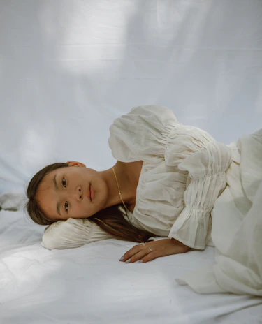 A relaxed model lounging in comfortable, elegant pajamas with soft natural light.