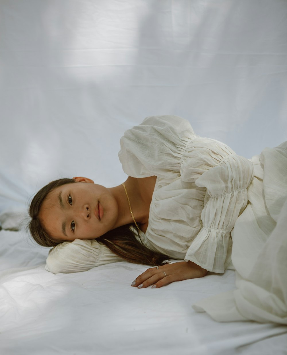 침대에 누워 있는 하얀 드레스 셔츠를 입은 여자
