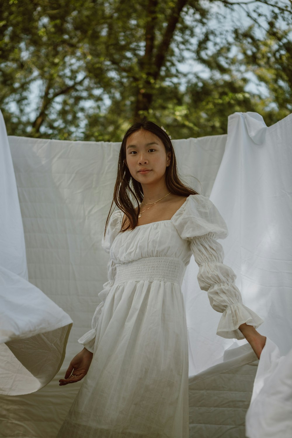 woman in white long sleeve dress standing near white curtain