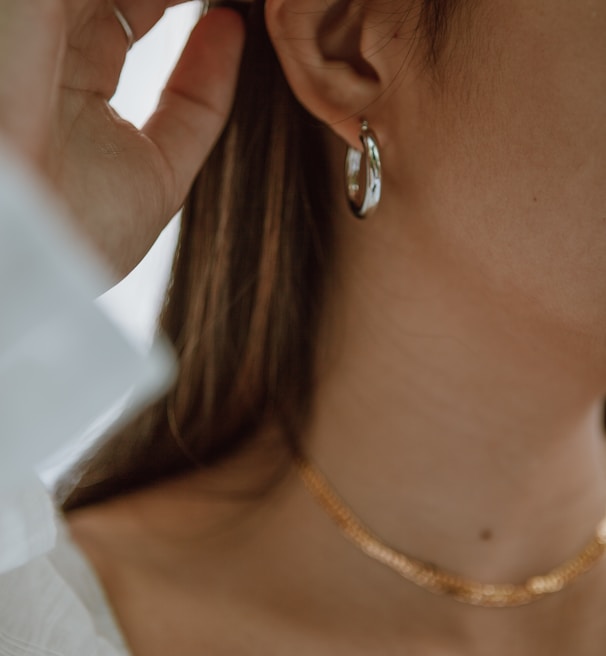 woman in white shirt wearing gold necklace