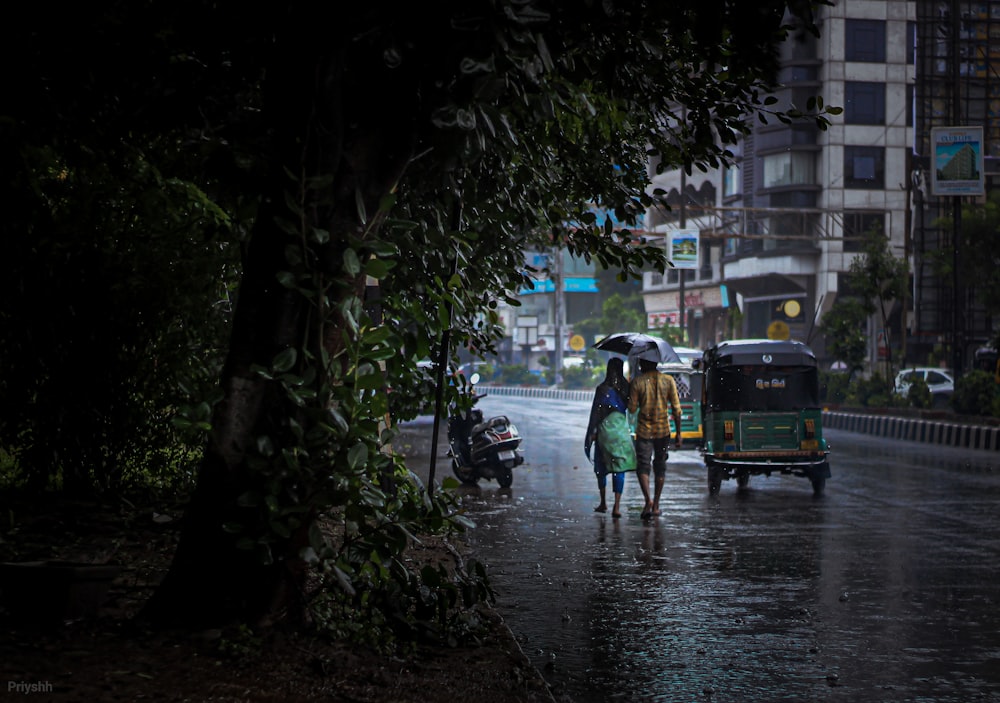 a couple of people walking down a rain soaked street