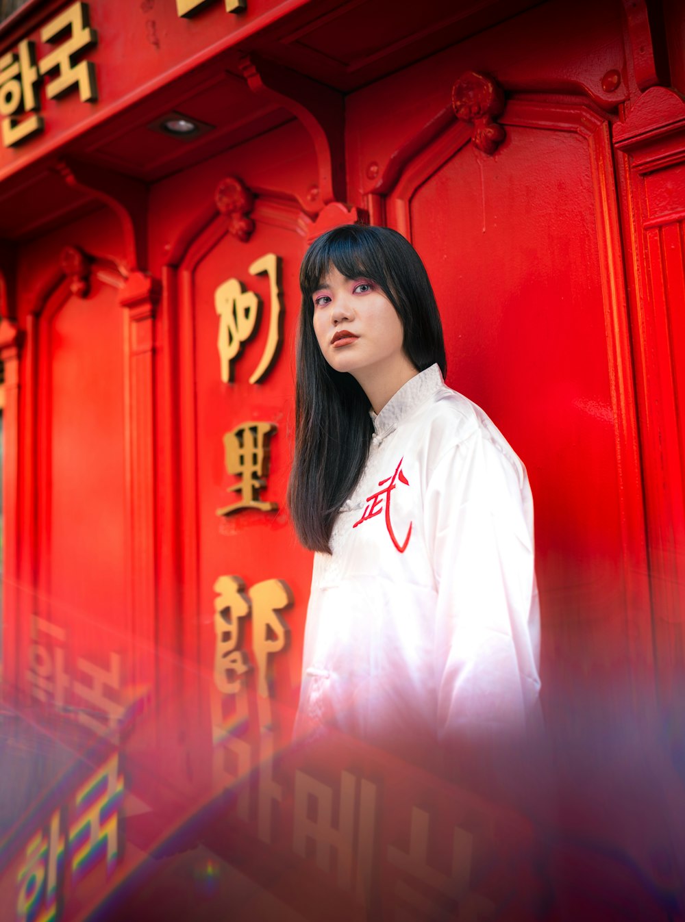 woman in white button up shirt standing near red door
