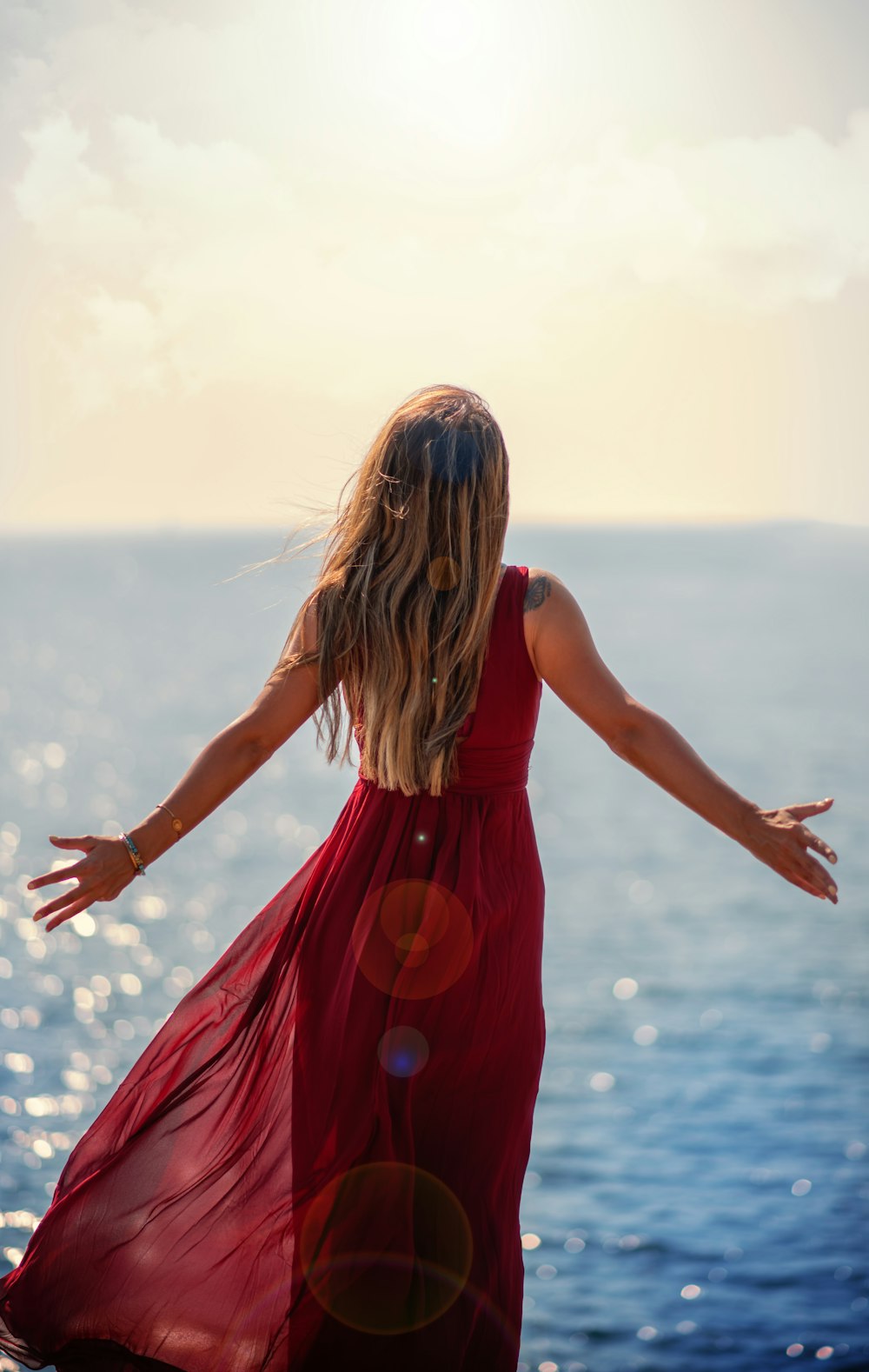 woman in red sleeveless dress standing on water during daytime