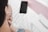 A person with earphones is gazing at a smartphone placed on a bed. A card or box labeled 'Swappie' is nearby, partially visible. The setting appears casual, suggesting a relaxed environment.