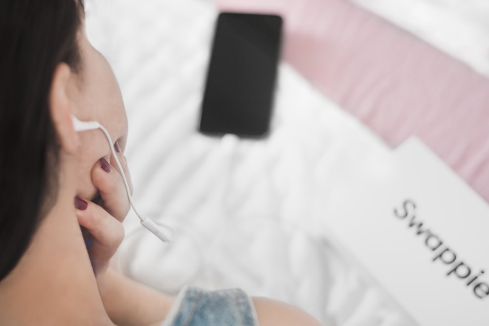 person in blue denim shorts holding white earbuds