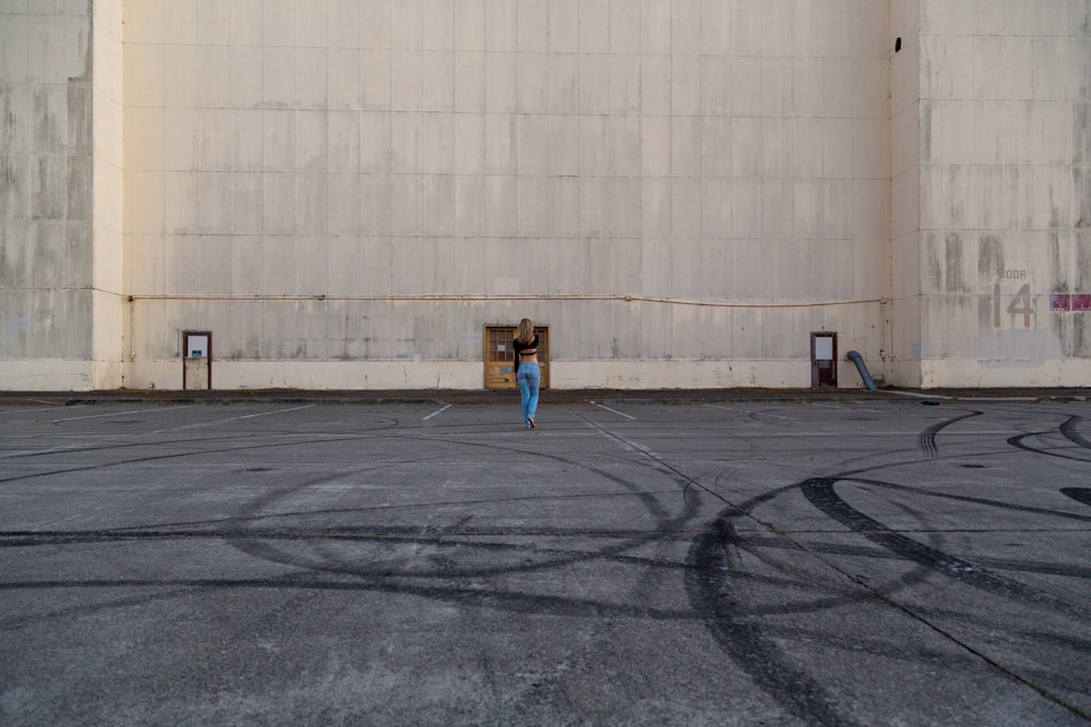 person in blue jacket and black pants standing on gray concrete floor