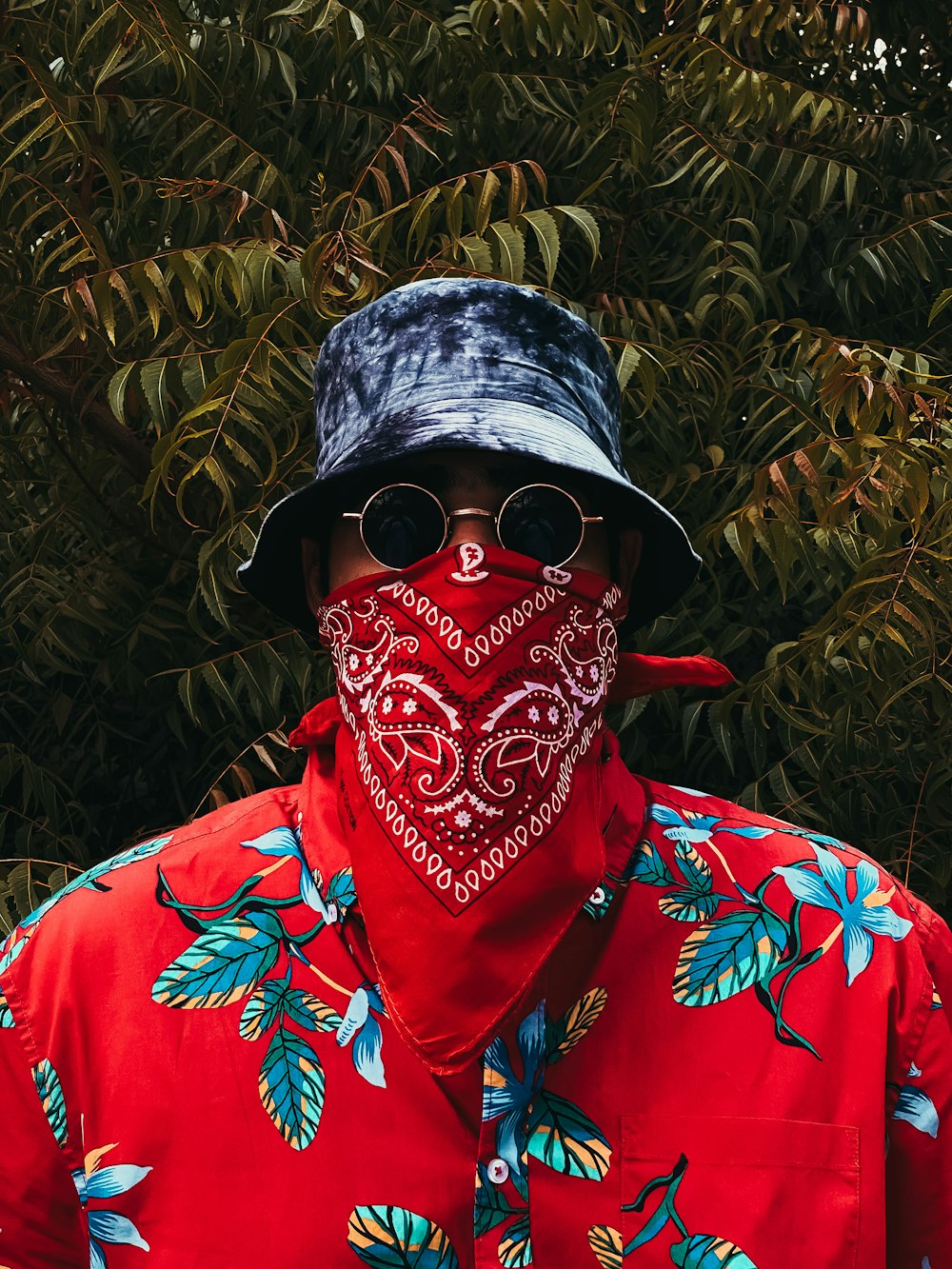 person in red and white floral dress shirt wearing black sunglasses