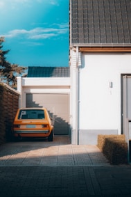 yellow car parked beside white building