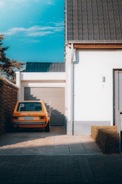 yellow car parked beside white building