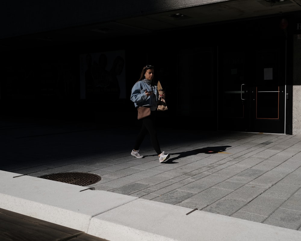 man in blue t-shirt and black shorts standing on sidewalk during nighttime