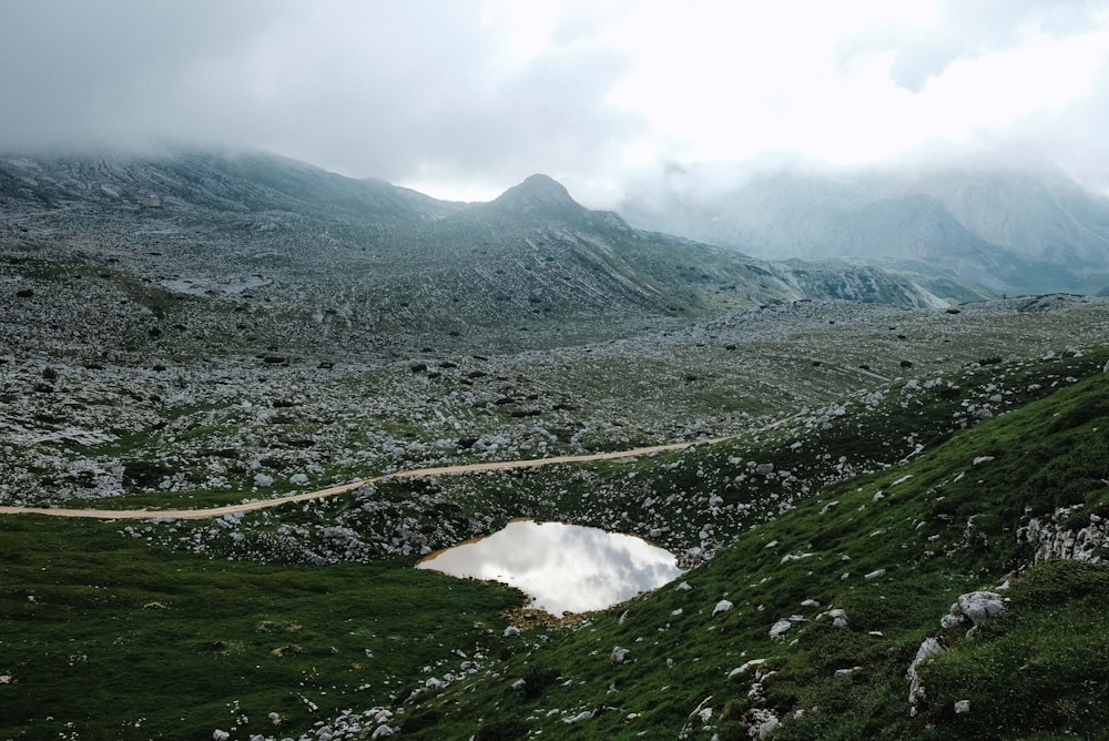 green grass field and mountain under white clouds during daytime