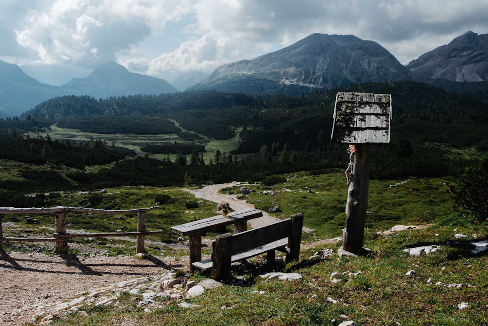 brown wooden bench on green grass field near mountain during daytime