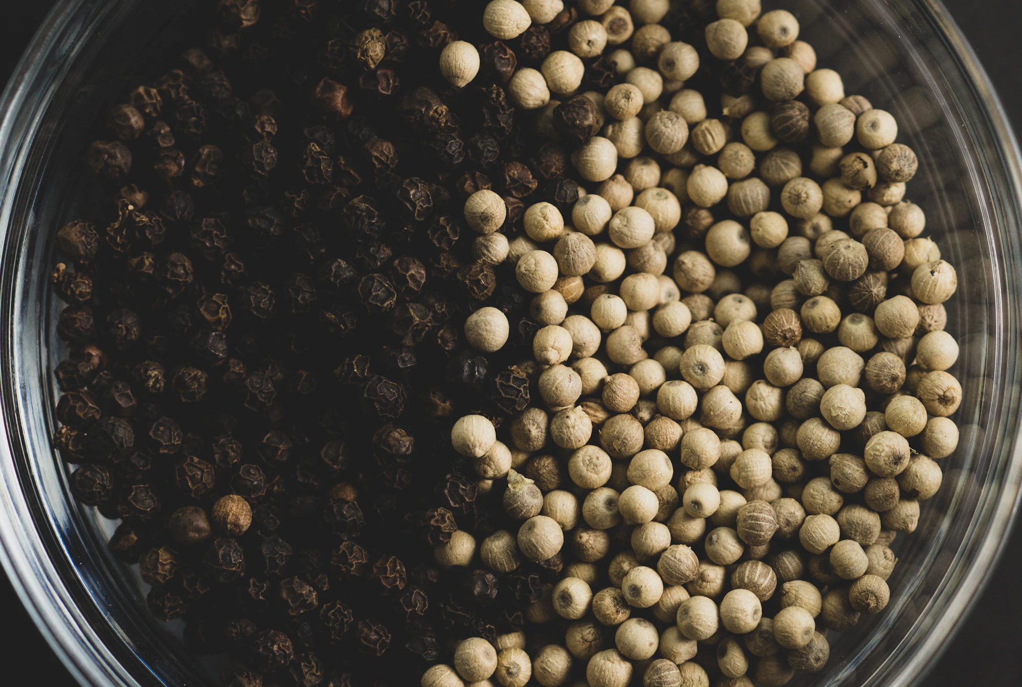 Black and white peppercorns in a glass bowl