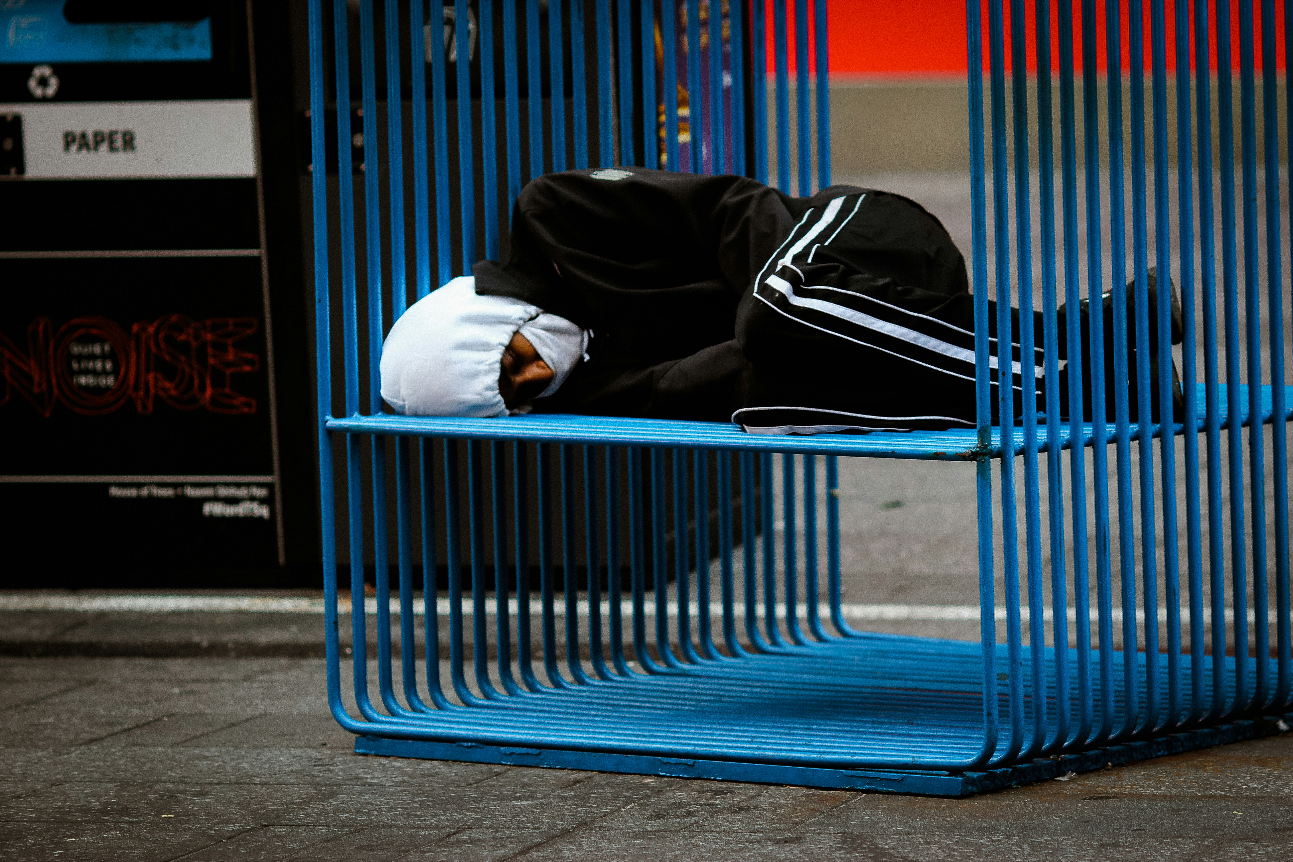 man in black jacket sitting on blue bench